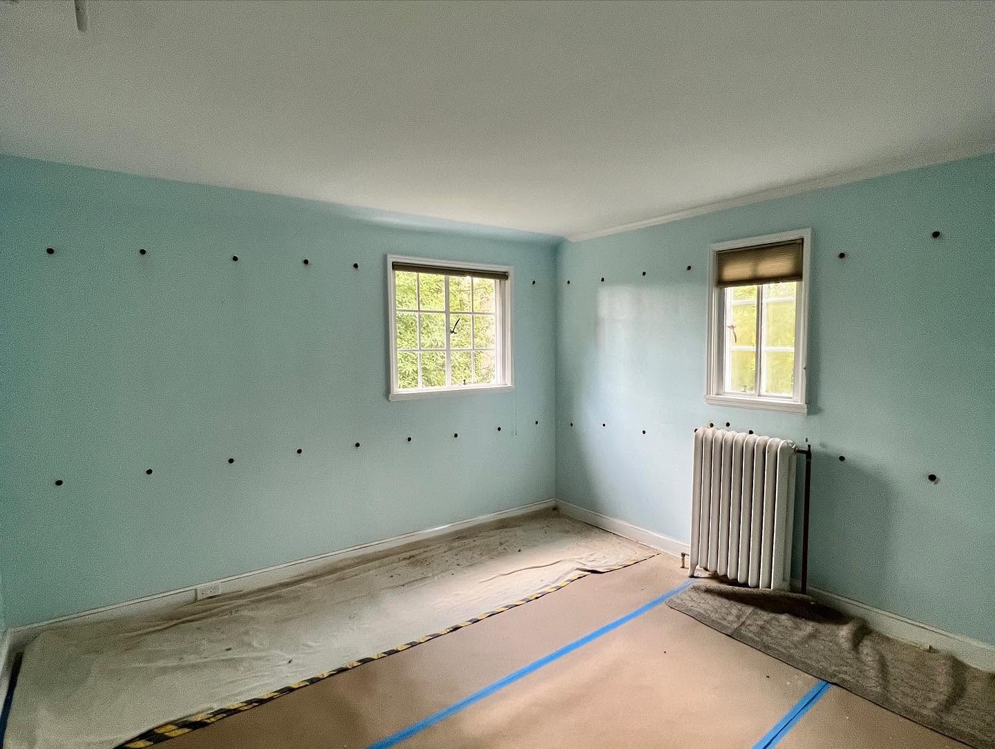 Small insulation access holes in a blue room with protected floors